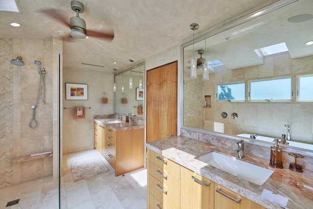 bathroom with vanity, a tile shower, ceiling fan, a skylight, and tile patterned floors