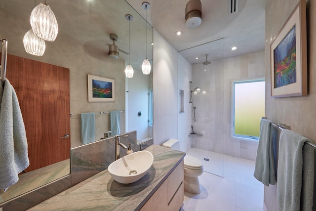 bathroom featuring tile patterned floors, tiled shower, vanity, and toilet