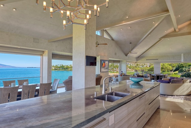 kitchen featuring hanging light fixtures, high vaulted ceiling, beam ceiling, dark stone counters, and sink