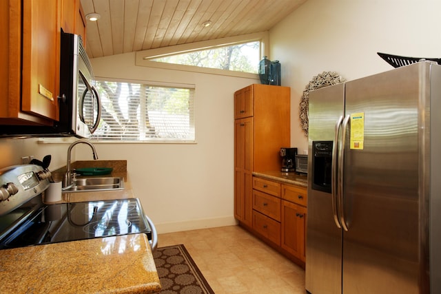 kitchen featuring light stone countertops, sink, stainless steel appliances, and vaulted ceiling