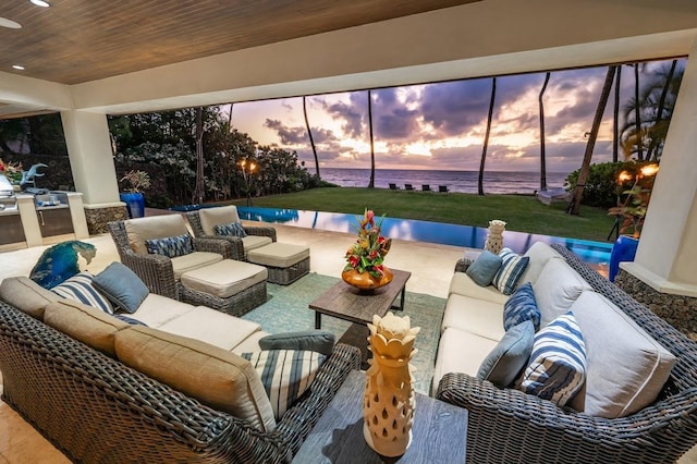 patio terrace at dusk featuring an outdoor hangout area and a water view