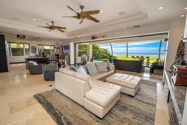 living room featuring a water view and a raised ceiling