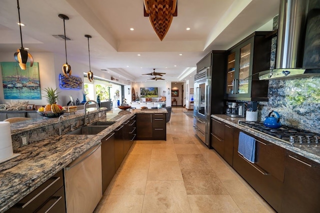 kitchen with pendant lighting, sink, a tray ceiling, stainless steel appliances, and dark stone counters