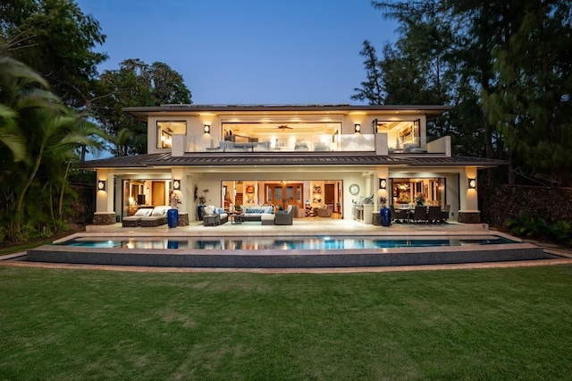 back house at dusk with an outdoor hangout area, a yard, and a balcony