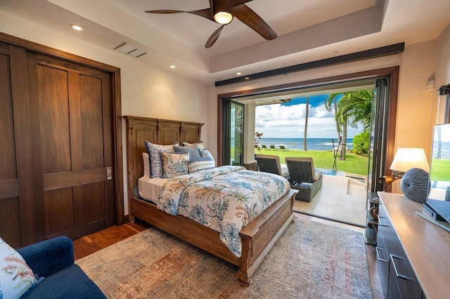 bedroom with ceiling fan, dark wood-type flooring, and a raised ceiling