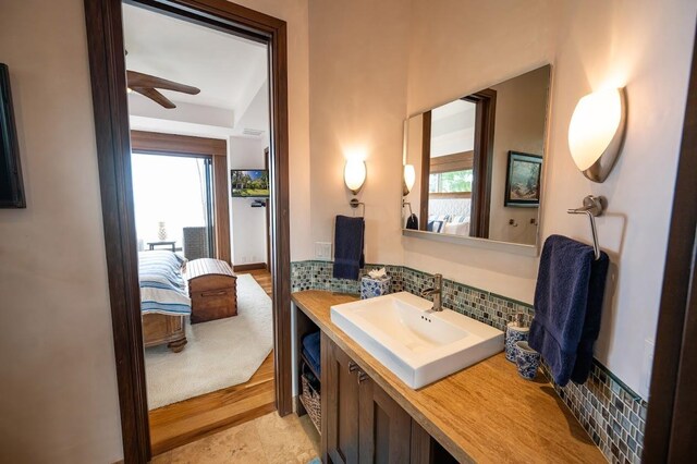 bathroom featuring ceiling fan, a healthy amount of sunlight, backsplash, and vanity