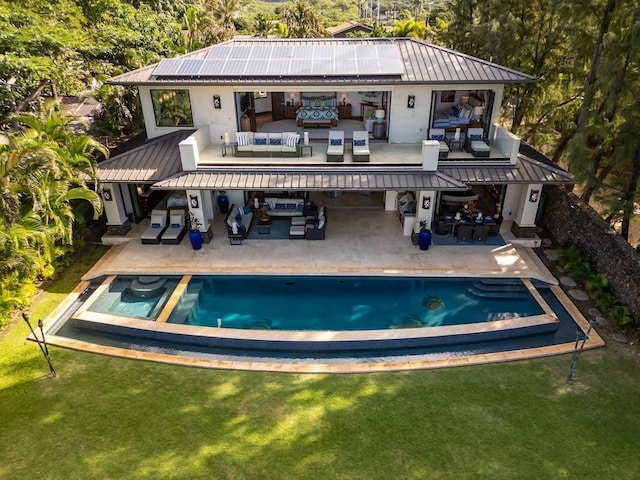 rear view of property featuring an outdoor hangout area, a yard, a patio area, and solar panels