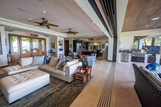 tiled living room with a wealth of natural light, a raised ceiling, and french doors