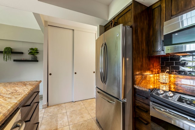 kitchen featuring appliances with stainless steel finishes, light tile patterned floors, and light stone counters