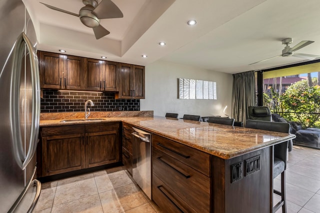 kitchen featuring a breakfast bar, sink, ceiling fan, kitchen peninsula, and stainless steel appliances