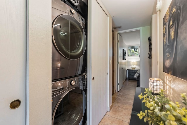 clothes washing area featuring stacked washer / drying machine and light tile patterned flooring