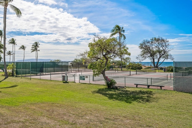 view of sport court with a water view and a yard