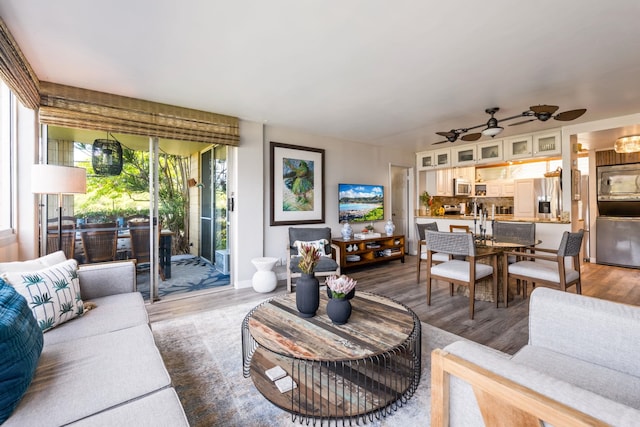 living room with a ceiling fan, a wealth of natural light, and wood finished floors