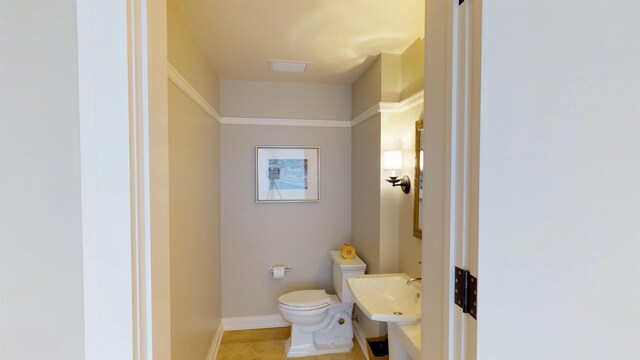half bathroom with tile patterned flooring, toilet, baseboards, and a sink