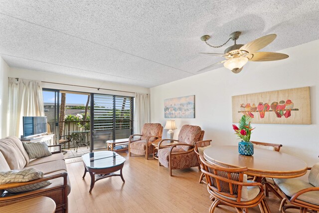 living room with ceiling fan, a textured ceiling, and light wood-type flooring