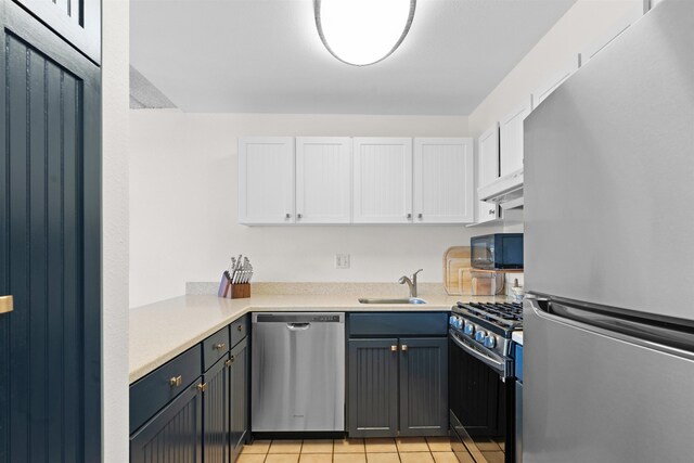 kitchen with exhaust hood, white cabinets, sink, light tile patterned floors, and appliances with stainless steel finishes