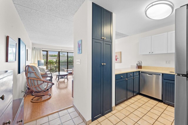 kitchen featuring blue cabinets, a textured ceiling, light hardwood / wood-style floors, white cabinetry, and stainless steel appliances