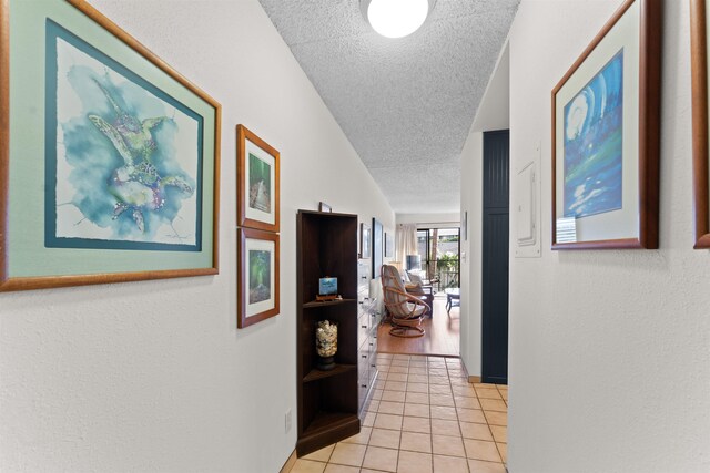 corridor featuring light tile patterned floors and a textured ceiling