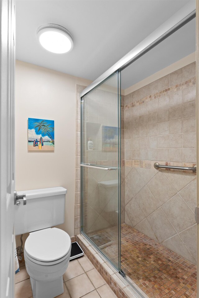 bathroom featuring tile patterned floors, a shower with door, and toilet