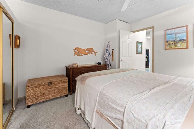 carpeted bedroom featuring ceiling fan, a closet, and a textured ceiling