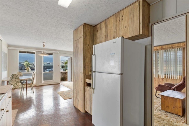 kitchen with hanging light fixtures, a textured ceiling, and white fridge