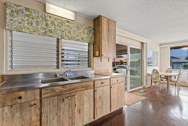 kitchen with stainless steel counters, sink, and a textured ceiling