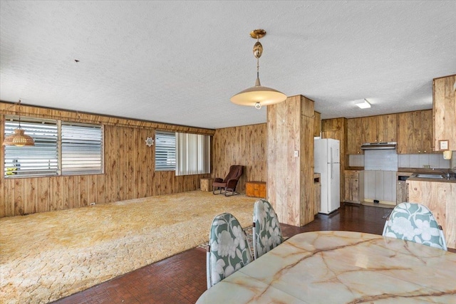 dining space featuring sink, a textured ceiling, and wooden walls