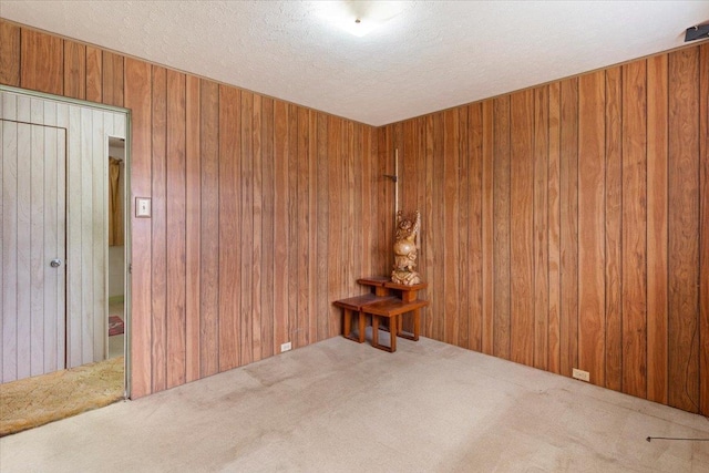 spare room with wooden walls, a textured ceiling, and carpet flooring