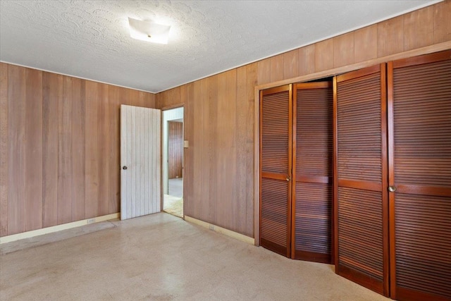 unfurnished bedroom featuring a closet, a textured ceiling, and wood walls