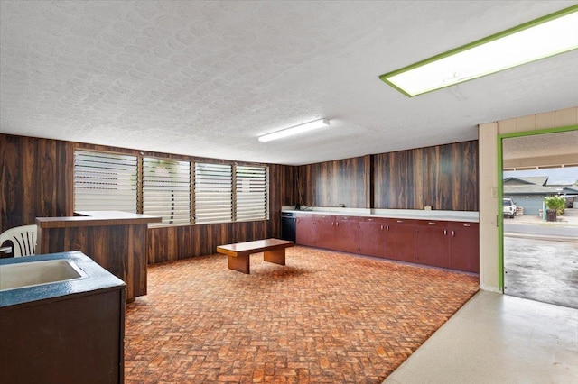 misc room featuring wooden walls, sink, and a textured ceiling