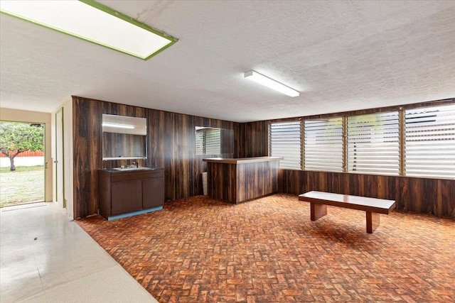 interior space featuring sink, wooden walls, and a textured ceiling