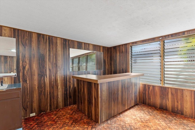 interior space with a textured ceiling and wood walls