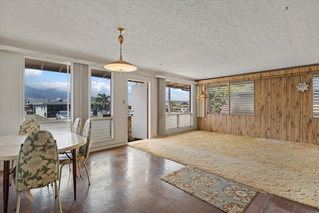 dining area with a mountain view, a textured ceiling, and wood walls