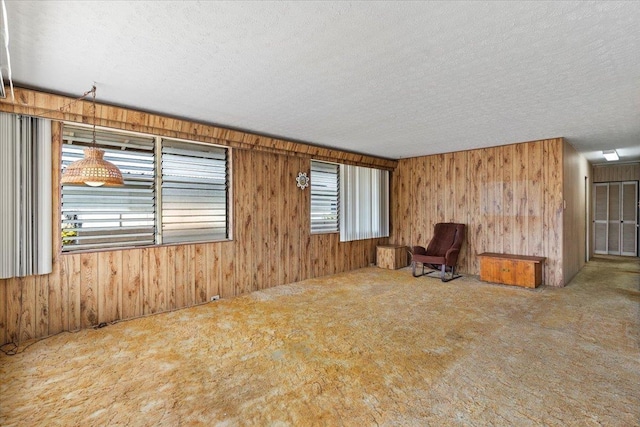 carpeted empty room featuring a textured ceiling and wood walls