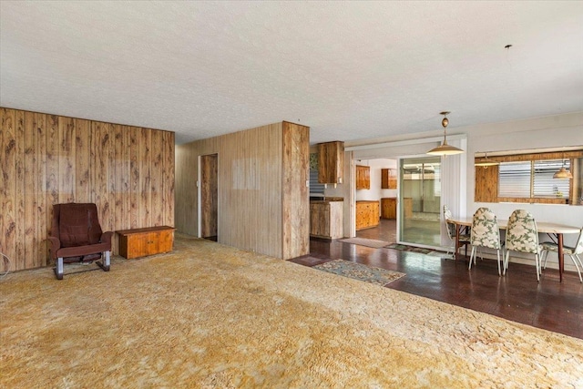 unfurnished living room with a textured ceiling and wooden walls