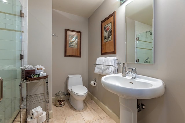 bathroom featuring tile patterned flooring, a shower with shower door, and toilet