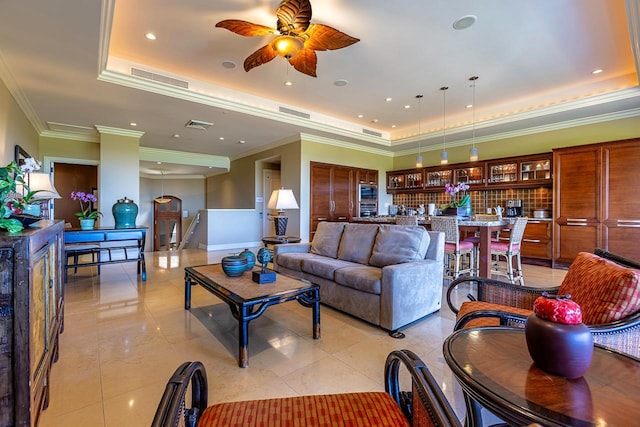 living room featuring ornamental molding, a tray ceiling, and ceiling fan