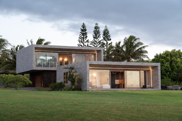 back of house featuring a balcony and a lawn