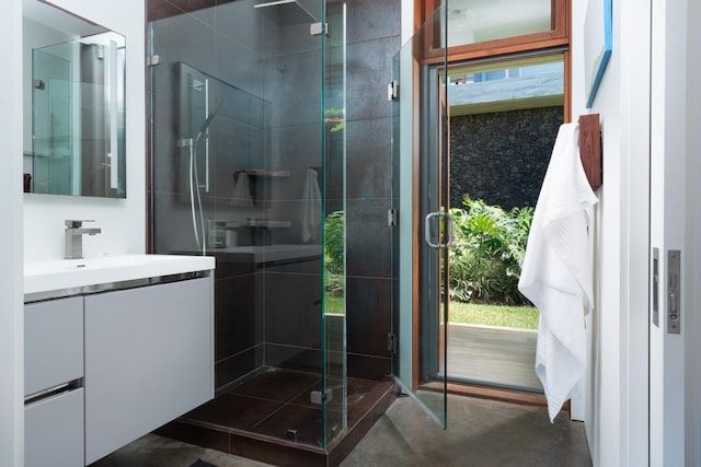 bathroom featuring a shower with door and vanity