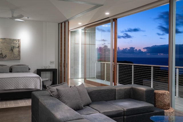 bedroom with ceiling fan, a wall of windows, and a water view