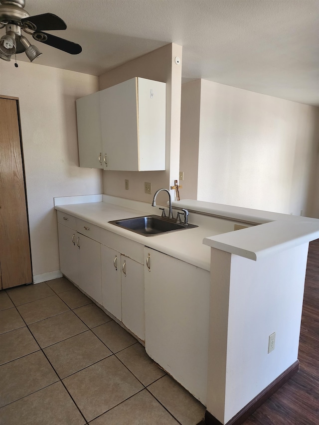 kitchen with a textured ceiling, dark hardwood / wood-style floors, sink, white cabinets, and kitchen peninsula