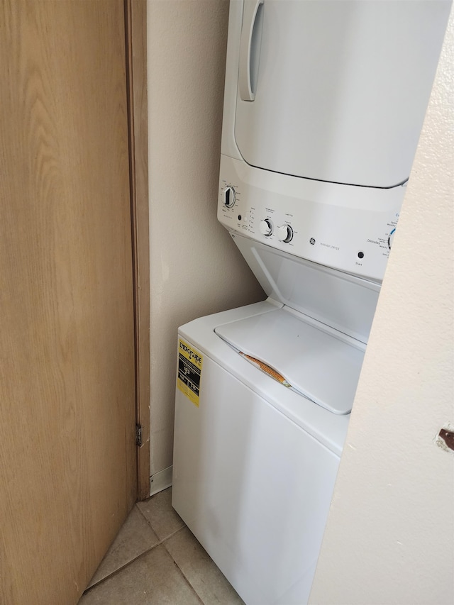 laundry room featuring stacked washing maching and dryer and light tile patterned floors