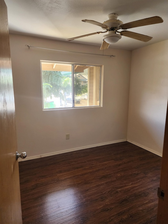 spare room with dark hardwood / wood-style flooring and ceiling fan