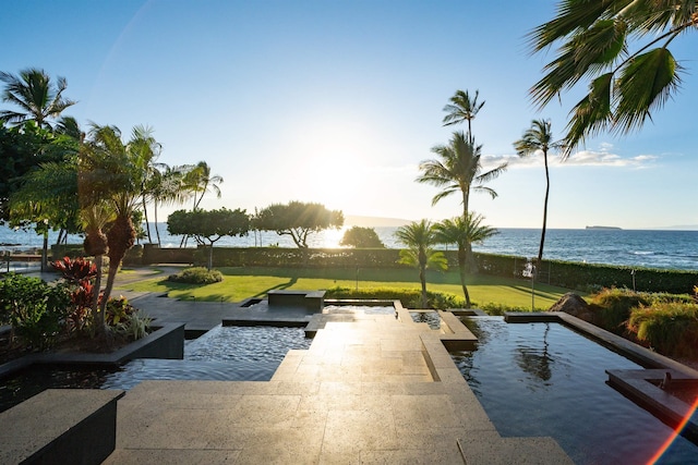 view of swimming pool with a lawn and a water view