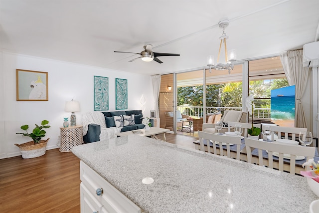 kitchen featuring light stone countertops, a wall mounted AC, white cabinets, dark hardwood / wood-style floors, and hanging light fixtures