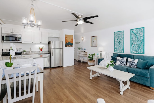 kitchen featuring appliances with stainless steel finishes, light wood-type flooring, sink, decorative light fixtures, and white cabinetry