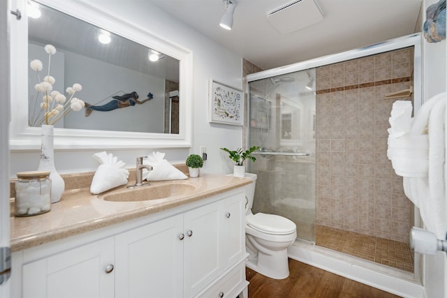 bathroom featuring vanity, hardwood / wood-style flooring, toilet, and a shower with door