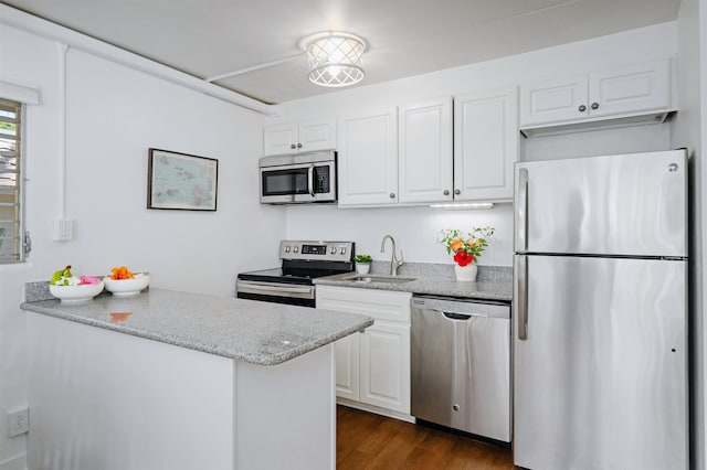 kitchen with sink, dark hardwood / wood-style floors, appliances with stainless steel finishes, light stone counters, and white cabinetry