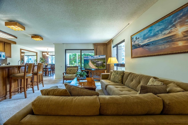 living room featuring light carpet, a textured ceiling, and a notable chandelier