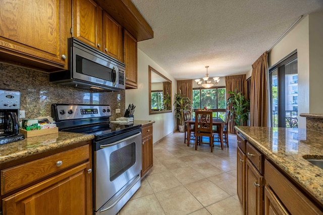 kitchen featuring decorative backsplash, a textured ceiling, a notable chandelier, light tile patterned flooring, and stainless steel appliances